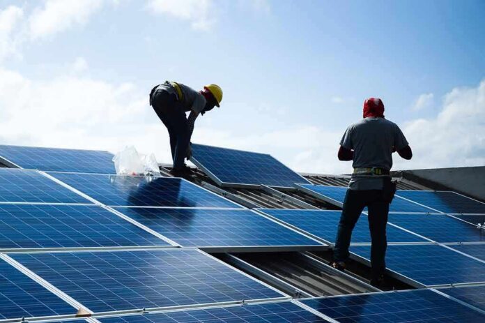 shutterstock_1056264089 Workers installing solar panels on a rooftop