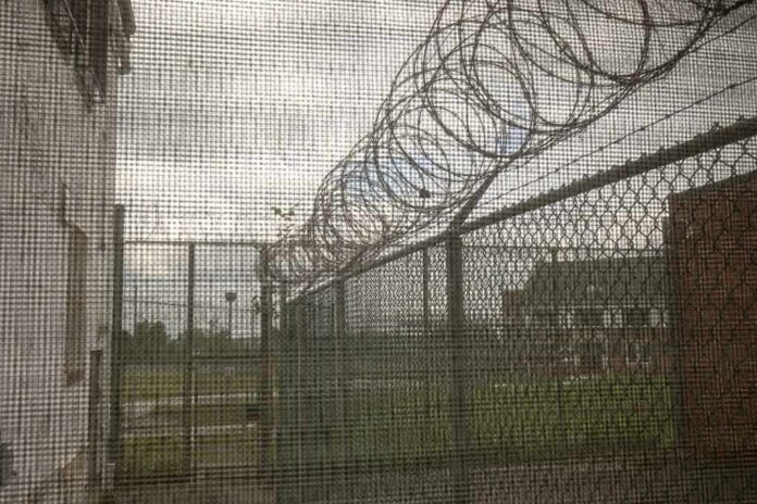 shutterstock_1105276424 Barbed wire on chain-link fence at a prison yard
