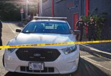 LA Mall Ambush Stuns Shoppers Police car behind yellow caution tape on a city street