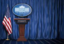 Pump Prices Soar—Industry Summoned to Answer White House press briefing podium with U.S. flag and blue curtain