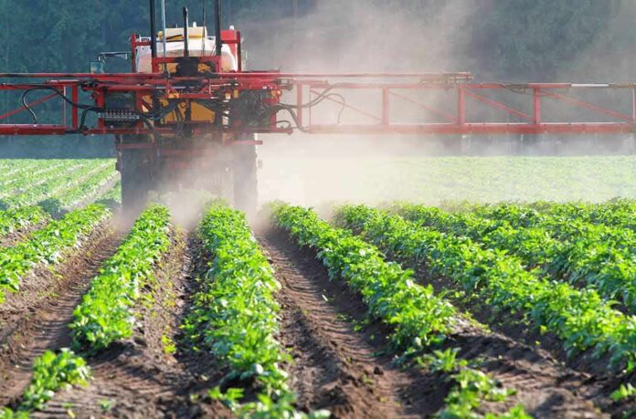 Crop sprayer applies mist over green rows of plants
