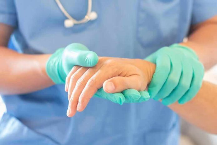 Healthcare worker in gloves holding a patient's hand