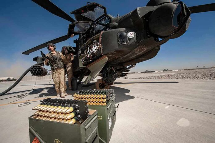 shutterstock_1229093764 attack helicopter on tarmac with crew and ammunition crates