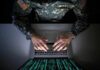 Soldier in camouflage typing on a laptop