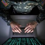 Town Rejects $10K ‘Bribe’ – What’s Hidden? Soldier in camouflage typing on a laptop