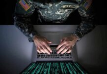 Town Rejects $10K ‘Bribe’ – What’s Hidden? Soldier in camouflage typing on a laptop