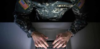 Soldier in camouflage typing on a laptop