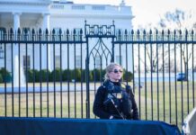 Security officer stands guard outside a large white government building