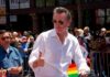 Grand Jury Probes Newsom’s Luxury Travel Man in white shirt giving thumbs up at a pride parade