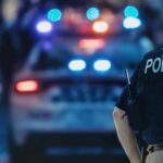 Miami High-Rise Horror: Mom Down police officer in vest near patrol car with flashing lights