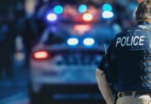 Miami High-Rise Horror: Mom Down police officer in vest near patrol car with flashing lights