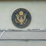 Sudden Escalation Warning Rattles Travelers U.S. embassy seal on a building wall