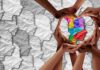Hands forming a heart around a colorful paper silhouette