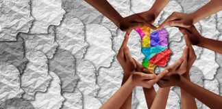 Hands forming a heart around a colorful paper silhouette