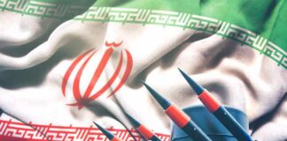 Iranian flag behind a battery of missiles and radar equipment