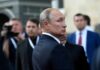 Russia Opens Vote Amid War And Restrictions man in suit looking back in a crowd