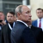 Russia Opens Vote Amid War And Restrictions man in suit looking back in a crowd