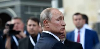 Russia Opens Vote Amid War And Restrictions man in suit looking back in a crowd