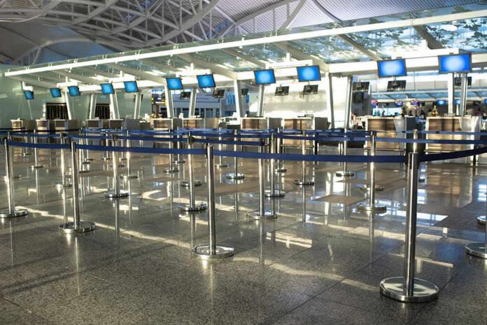 shutterstock_1668825886 Airport check-in counters with empty queue barriers