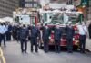 NYC Corner Becomes A 9/11 Honor Firefighters in dress uniforms salute in front of fire trucks