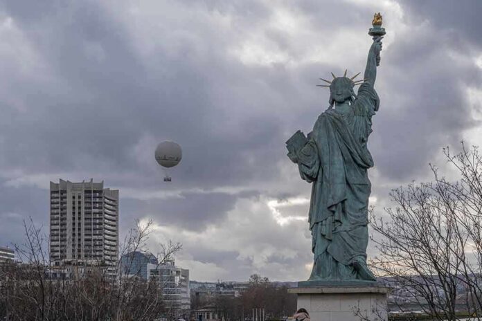 Statue of Liberty replica with cloudy sky and city buildings