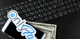 Smartphone with OnlyFans sticker and cash on a laptop keyboard