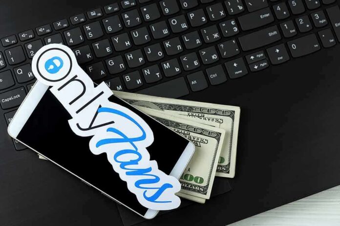 shutterstock_1941289663 Smartphone with OnlyFans sticker and cash on a laptop keyboard