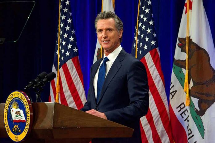 Man in suit speaking at a podium with American and California flags