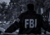 FBI agent in jacket facing a city street at dusk
