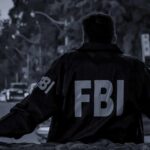 FBI agent in jacket facing a city street at dusk