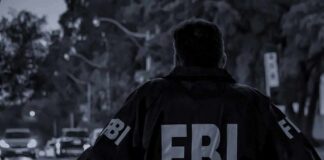 FBI agent in jacket facing a city street at dusk