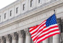American flag waves in front of a United States courthouse facade