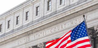 Justices Hit Brakes On Ballot Barcodes American flag waves in front of a United States courthouse facade