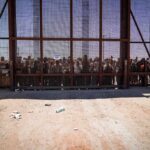 Could Spain Lose Schengen Access? Crowd stands behind tall metal fence at border crossing