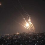 Houthis Target Saudi Sites, Officials Push Back Night sky above a city with multiple rockets arcing and bright explosions