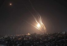 Houthis Target Saudi Sites, Officials Push Back Night sky above a city with multiple rockets arcing and bright explosions