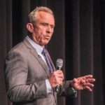 RFK Jr. Takes Aim At Democrats man in a suit speaking into a microphone on stage
