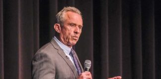 man in a suit speaking into a microphone on stage