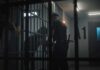 police officer at a jail cell with detainees behind bars