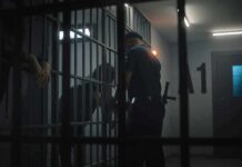 Hazing Dungeon Exposed at UW police officer at a jail cell with detainees behind bars