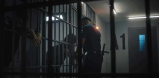 Hazing Dungeon Exposed at UW police officer at a jail cell with detainees behind bars