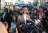 NYC Shock: Actor Targets City Hall Smiling man at outdoor press conference with microphones