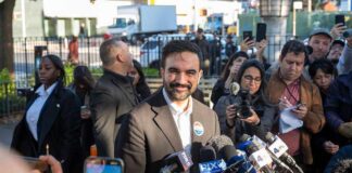 NYC Shock: Actor Targets City Hall Smiling man at outdoor press conference with microphones