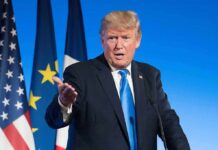 Fragile Truce Masks U.S.–China Tensions man in suit speaking at podium with flags behind