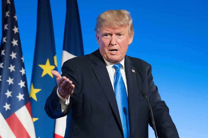 man in suit speaking at podium with flags behind
