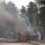 Ambulance Attacked After Deadly Pakistan Blast Burning vehicle on a smoke-filled street