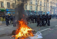 Tear Gas Clouds France’s Pay Crisis Fire burning on the street amid police presence.