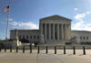 Supreme Court building with flag and people outside.