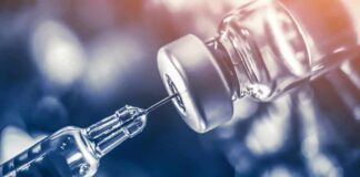 Deadly Outbreak Spurs Emergency Shot Blitz syringe needle drawing liquid from a vaccine vial