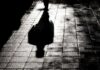 Silhouette shadow of a person walking on a wet pavement
